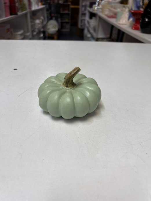 Small, sage-green decorative pumpkin figurine